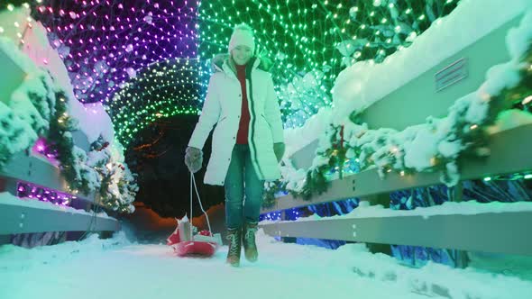 Happy Woman in Red Sweater Walking By Winter Wonderland with Christmas Gifts