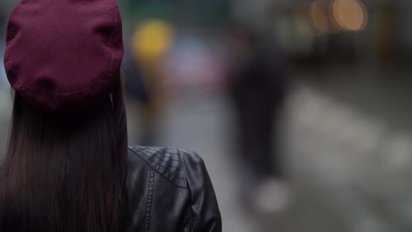 Confident Beautiful Business Woman in a Purple Hat and Leather Jacket Is Walking on a City Street