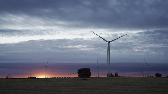Sunset with Modern Wind Turbines and Car Silhouette