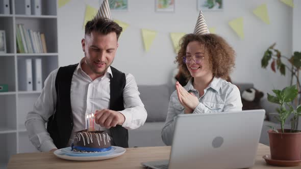 Celebrating Onlinehappy Boyfriend and Girlfriend in Holiday Caps Blowing Out Candles on Cake During