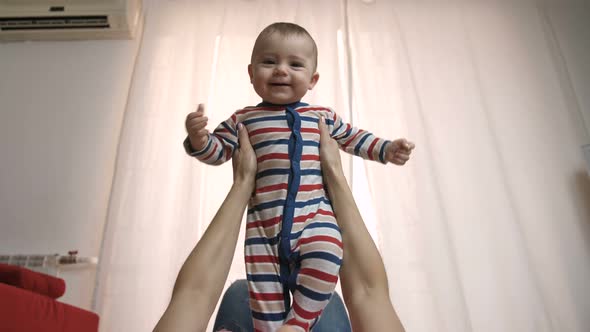 Mother's Arms Holding and Lifting Baby in the Air