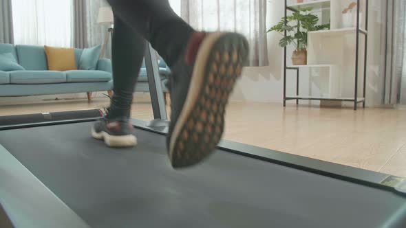 Back View Legs Of Asian Woman Running On A Treadmill At Home