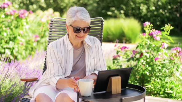 Happy Senior Woman with Tablet Pc at Summer Garden