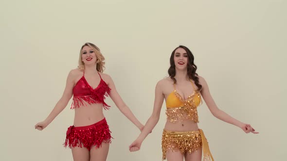 Two Adorable Cheerleaders in Red and Yellow Shiny Uniforms Dance a Gleeful Dance and Move Their Hips