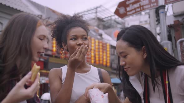 A group of multi-ethnic female friends enjoying street food on Yaowarat Road or Chinatown in Bangkok