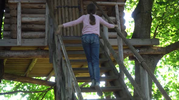 A Child Climbs the Wooden Steps to a Homemade Tree House to Play There