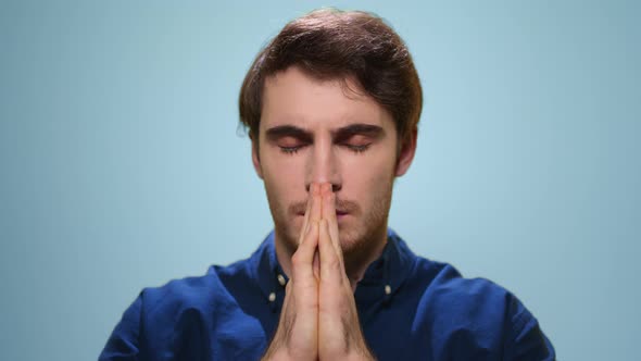 Handsome Man Praying in Studio. Serious Guy Holding Hands in Prayer Position