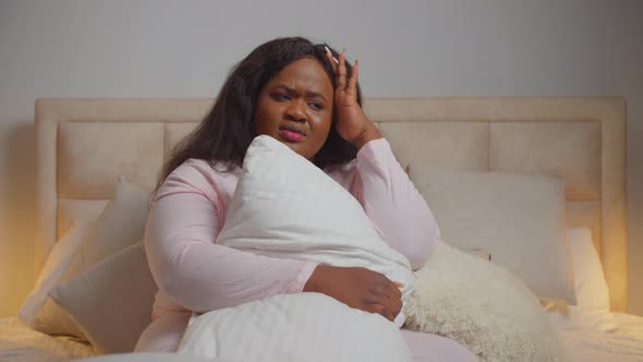 Upset African Woman Sitting Bed Hugging Pillow