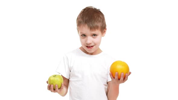 Smiling Caucasian Elementaryschool Aged Boy Standing on White Background with Apple and Orange in