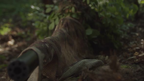 Closeup of Sniper Looking Through Scope of Optical Sight in Forest