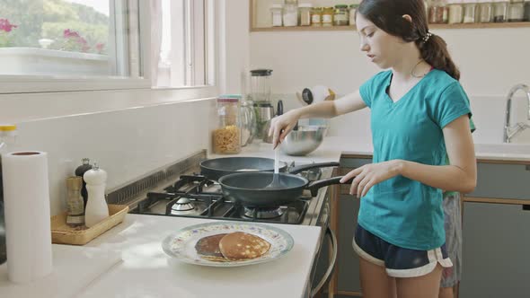 Young kids preparing pancakes in the kitchen using a frying pan