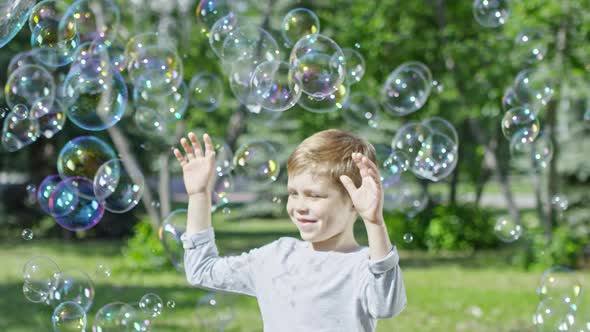 Happy Blonde Boy Enjoying Soap Bubbles alt