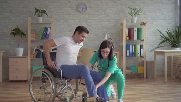 Girl Nurse Helps Disabled Person To Get Up From a Wheelchair