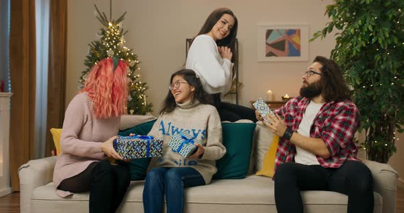 Fellow Students Sit on Sofa and Give Each Other Christmas Presents