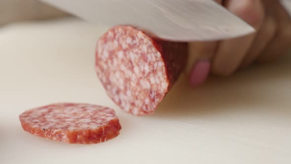 Salami cut on smaller pieces with knife 4K 2160p 30fps UltraHD footage - Cutting cured sausage of ai