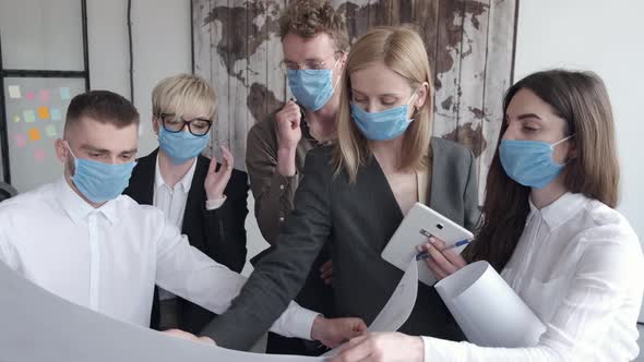 The Office Team in Masks Are Looking at the Progress Chart in the Office