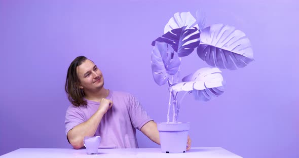 Young Man Admires Big Painted Potplant Sitting at Table