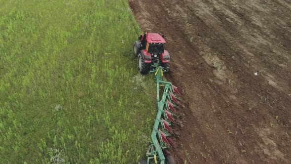 Farmer on an Energy Saturated Tractor Produces Plowing with a Turnover of the Soil Layer with a