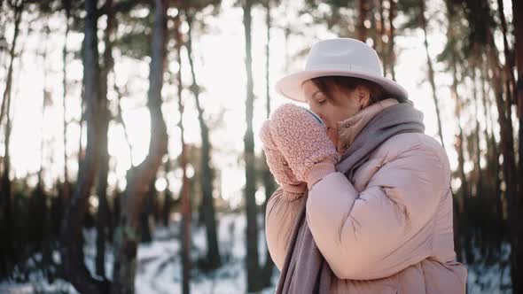 Beautiful Woman Having a Hot Drink in the Woods in Winter Enjoying Camp Life