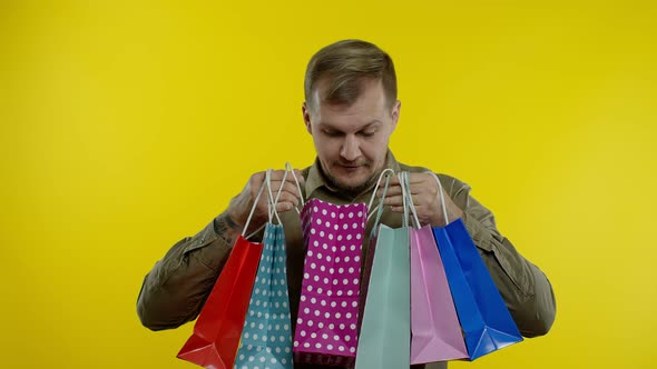 Man Raising Shopping Bags, Looking Satisfied with Purchase, Enjoying Discounts on Black Friday