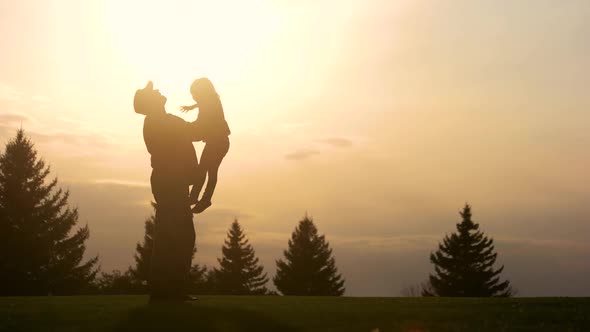 Father Lifting Up His Daughter in the Park While Sunset.