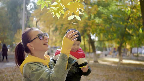 Young Mother Walking with a Little Son in Autumn Park. Happy Family in Autumn Par,