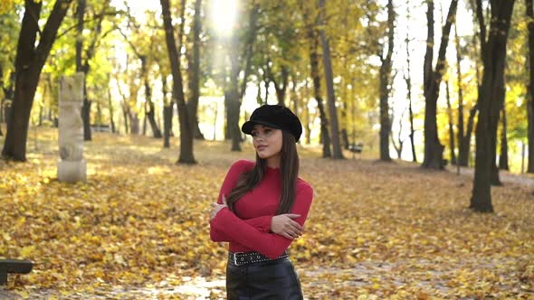 Young Happy Brunette in Beret Skirt Posing and Caressing Arms in Autumn Park