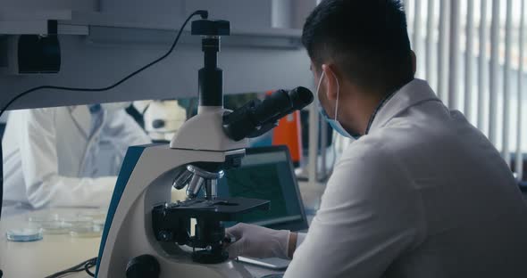 Scientist Studying Sample in Microscope