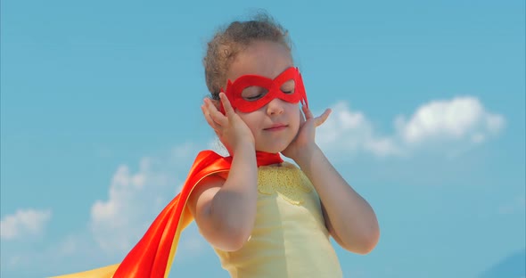 Beautiful Little Girl in the Superhero Costume, Dressed in a Red Cloak and the Mask of the Hero