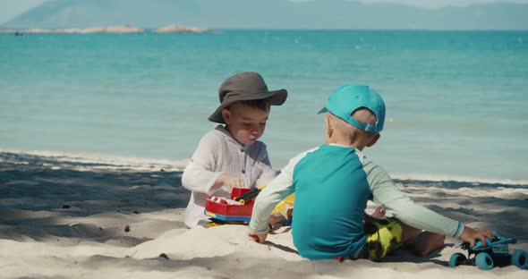 Children Play with a Plastic Crane and a Car on the Sand at the Beach