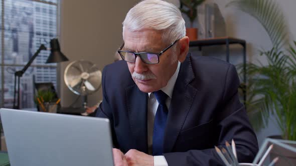 Focused Senior Business Man Entrepreneur Typing on Laptop Doing Research Sitting at Office Desk