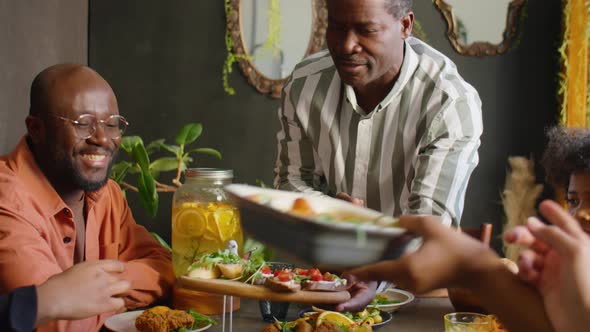 Black Man Serving Food for Guests at Home Family Dinner