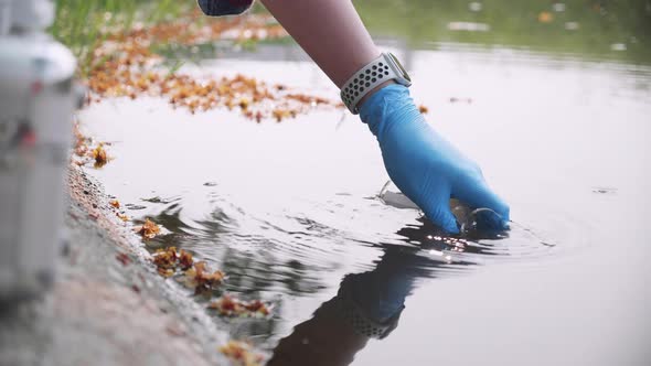 Scientist takes samples of factory wastewater in a test tube. Close up the hand.