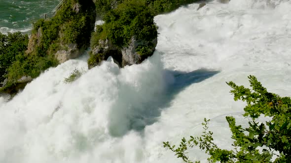 Smooth wide shot showing beautiful natural waterfall during sunny day in Switzerland