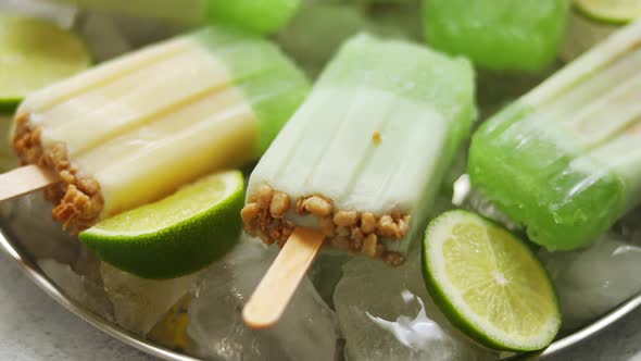 Lime and Cream Homemade Popsicles or Ice Creams Placed with Ice Cubes on Gray Stone Backdrop