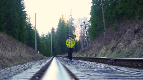 A Woman with a Backpack Walks on the Railway