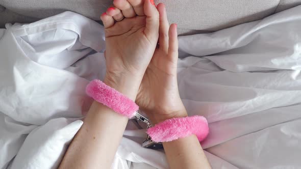 Pink Sexy Fluffy Handcuff Locked on Female Wrists, Closeup. Erotic Sex Game with Sexual Toy