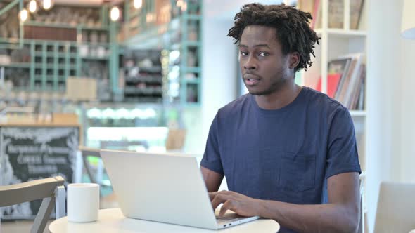 Thumbs Down By African Man with Laptop in Cafe