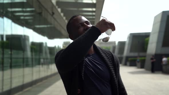 Portrait of an African Man in Dark Clothes and with a Beard. He Walks Along the Glass Wall of a City