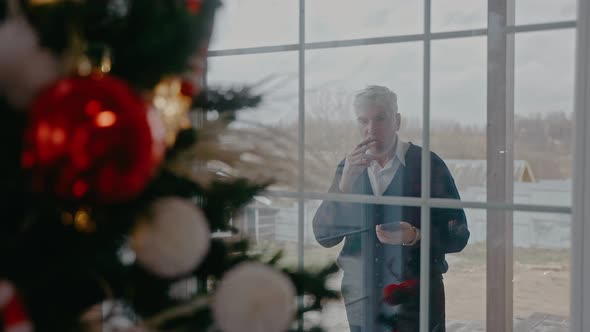 Grandad is Smoking Outside Looking Through the Window at Christmas Tree