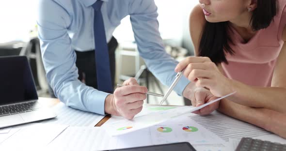 Adult Man and Woman are Looking at Documents in Office