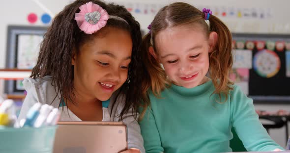 Front view of mixed-race schoolgirls studying on digital tablet in the classroom 4k