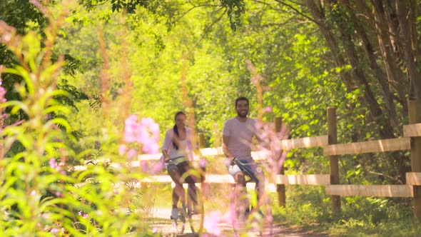 Happy Couple Riding Bicycles at Summer Park