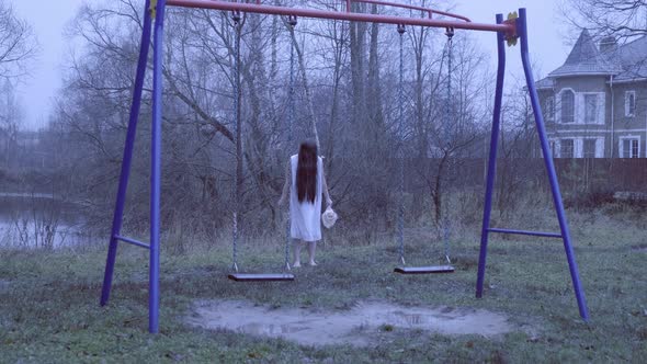 Ghost of Dead Girl Stands Behind Empty Swinging Swings.