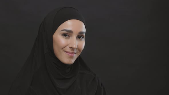 Young Happy Muslim Woman Wearing Black Hijab Smiling to Camera Posing Over Black Studio Background