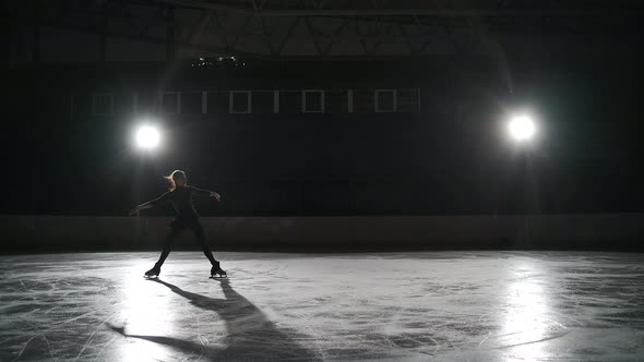 Single Figure Skater Lady is Performing Elements During Training on Ice Rink at Night Hard Workout