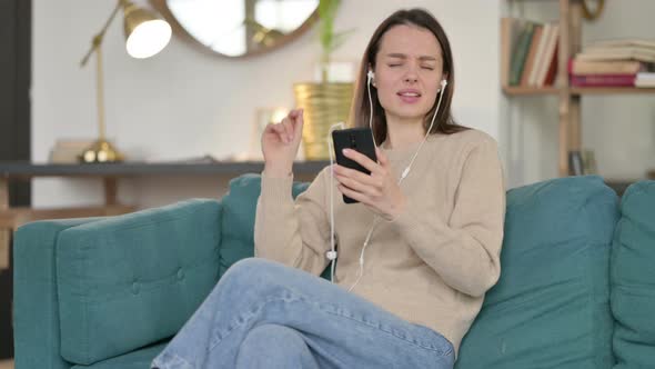 Young Woman Meditating Using Smartphone on Sofa