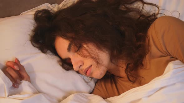 A Lovely Young Woman is Sleeping in the White Bed at Home
