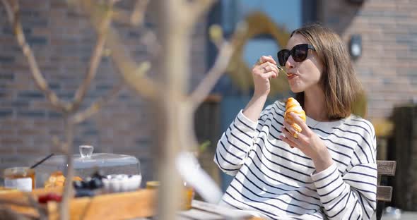 Woman Having a Breakfast with Croissants and Coffee Outdoors