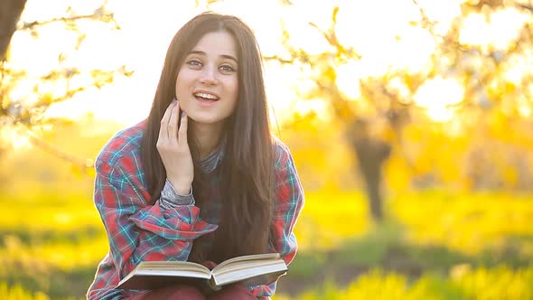 Brunet girl in shirt with notebook at apple tree garden. Spring time